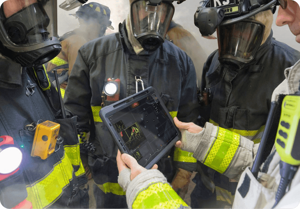 A team of firefighters gathered around a commander reviewing the Command Tablet during a live drill